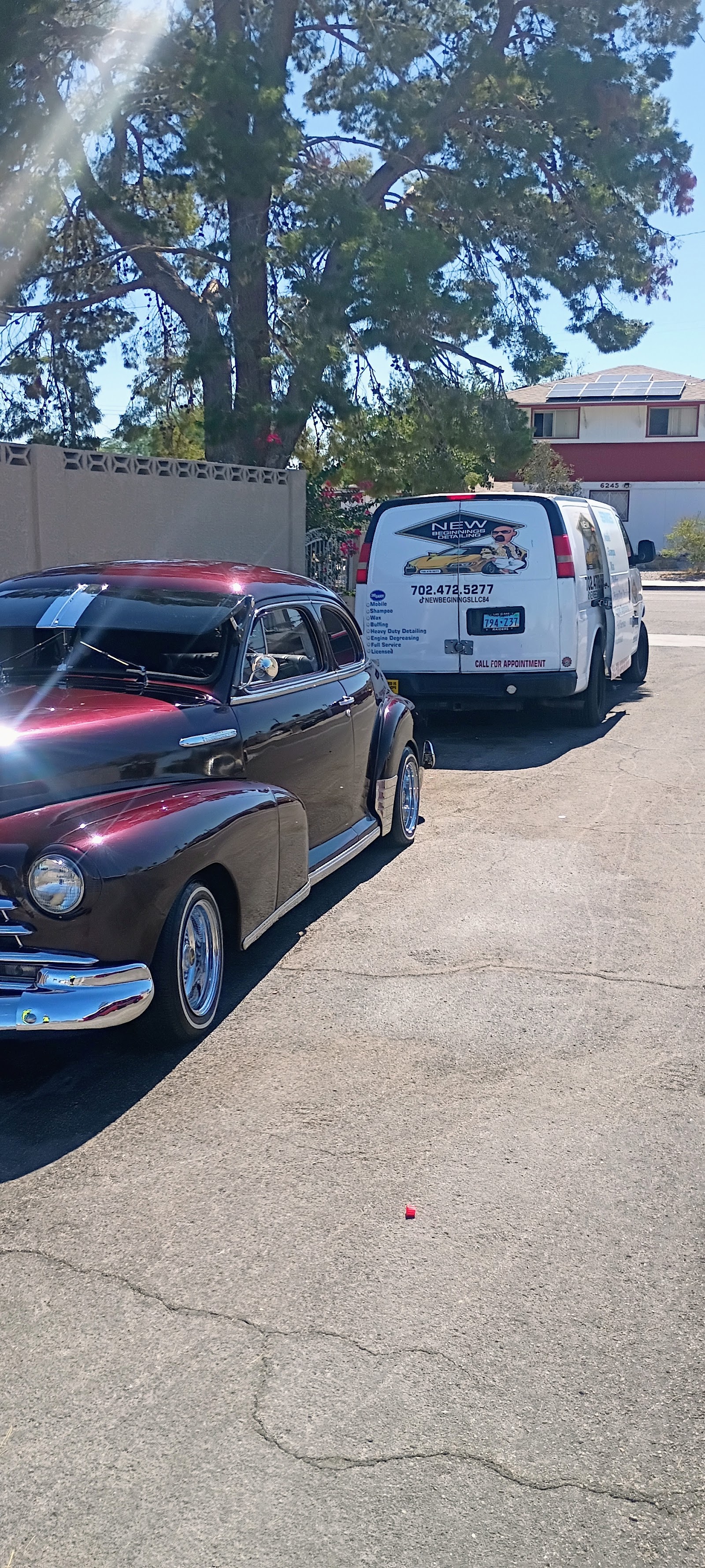 Company branded van parked next to a classic maroon lowrider car