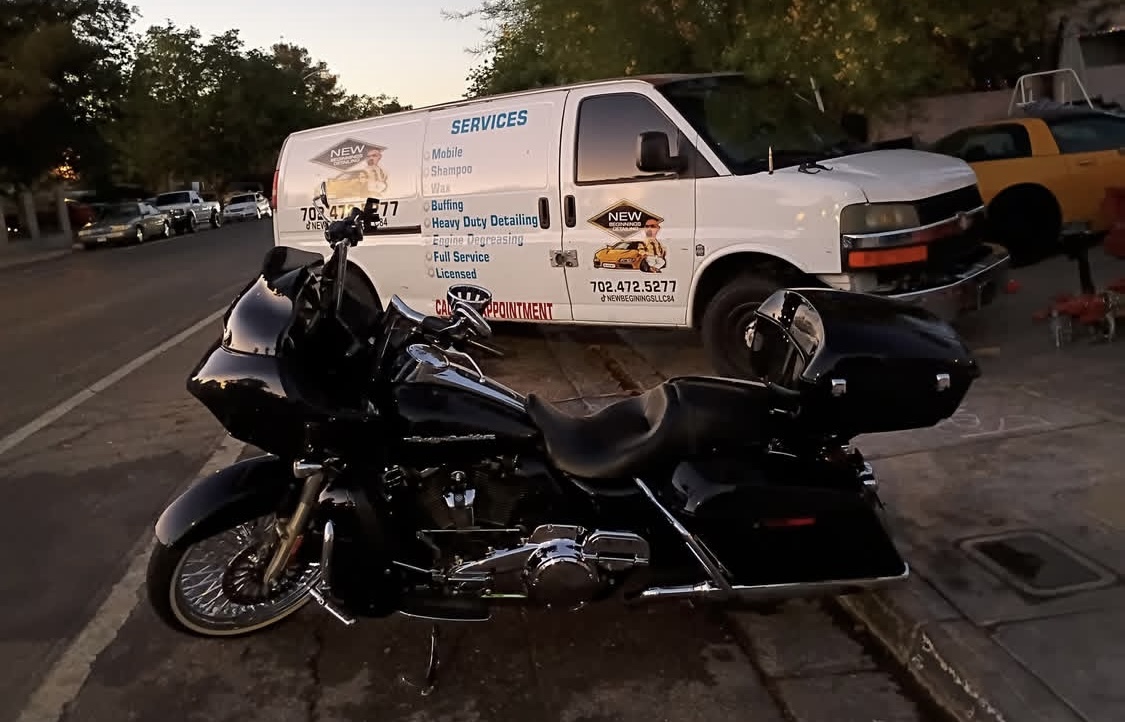 Black Harley-Davidson touring motorcycle in front of branded detailing van at dusk