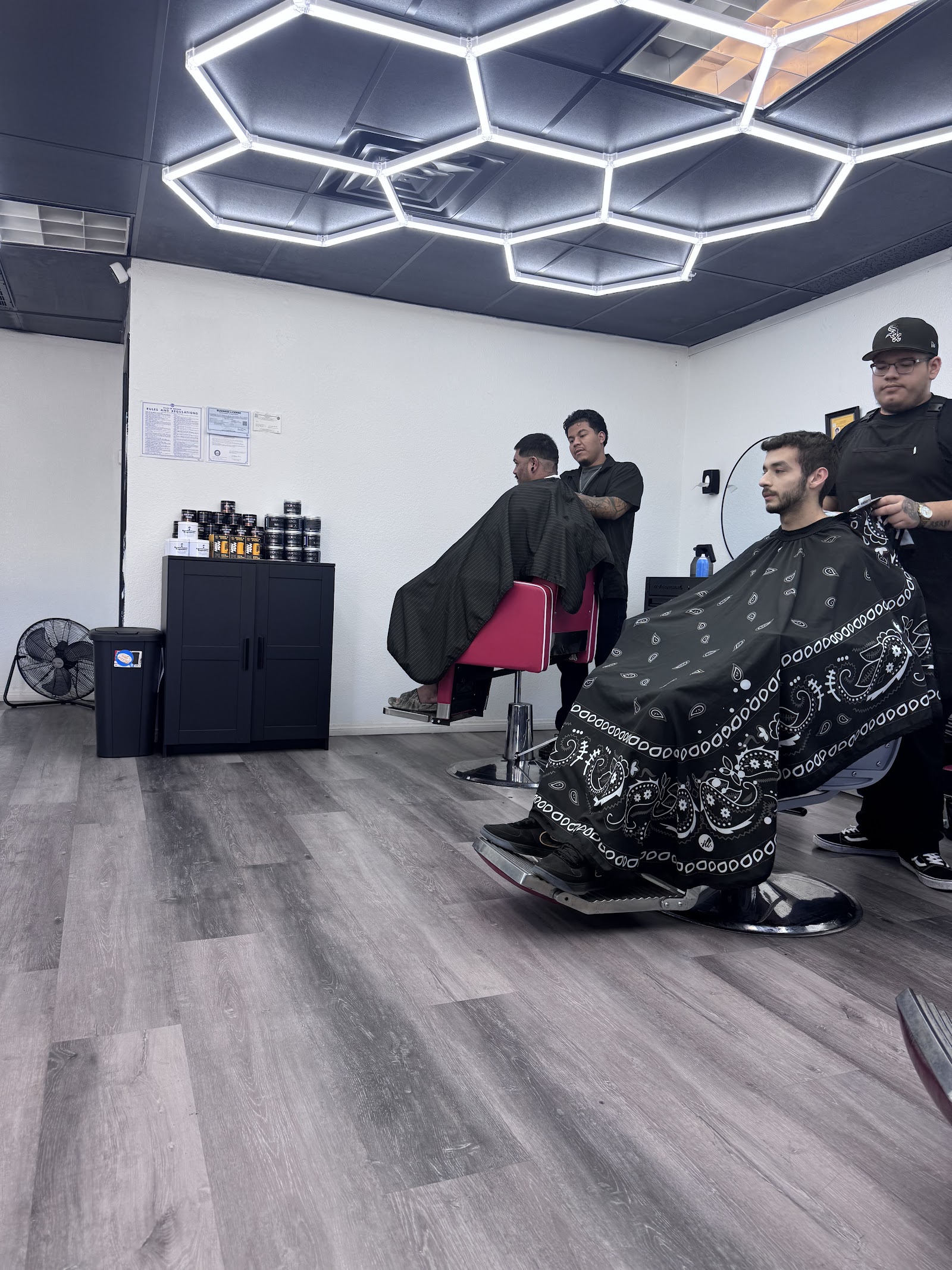 Barbershop interior with hexagon LED lighting, barbers cutting clients' hair
