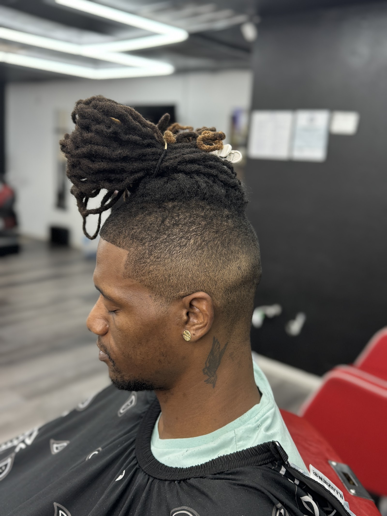 Man with dreadlocks pulled into top bun and clean burst fade sides
