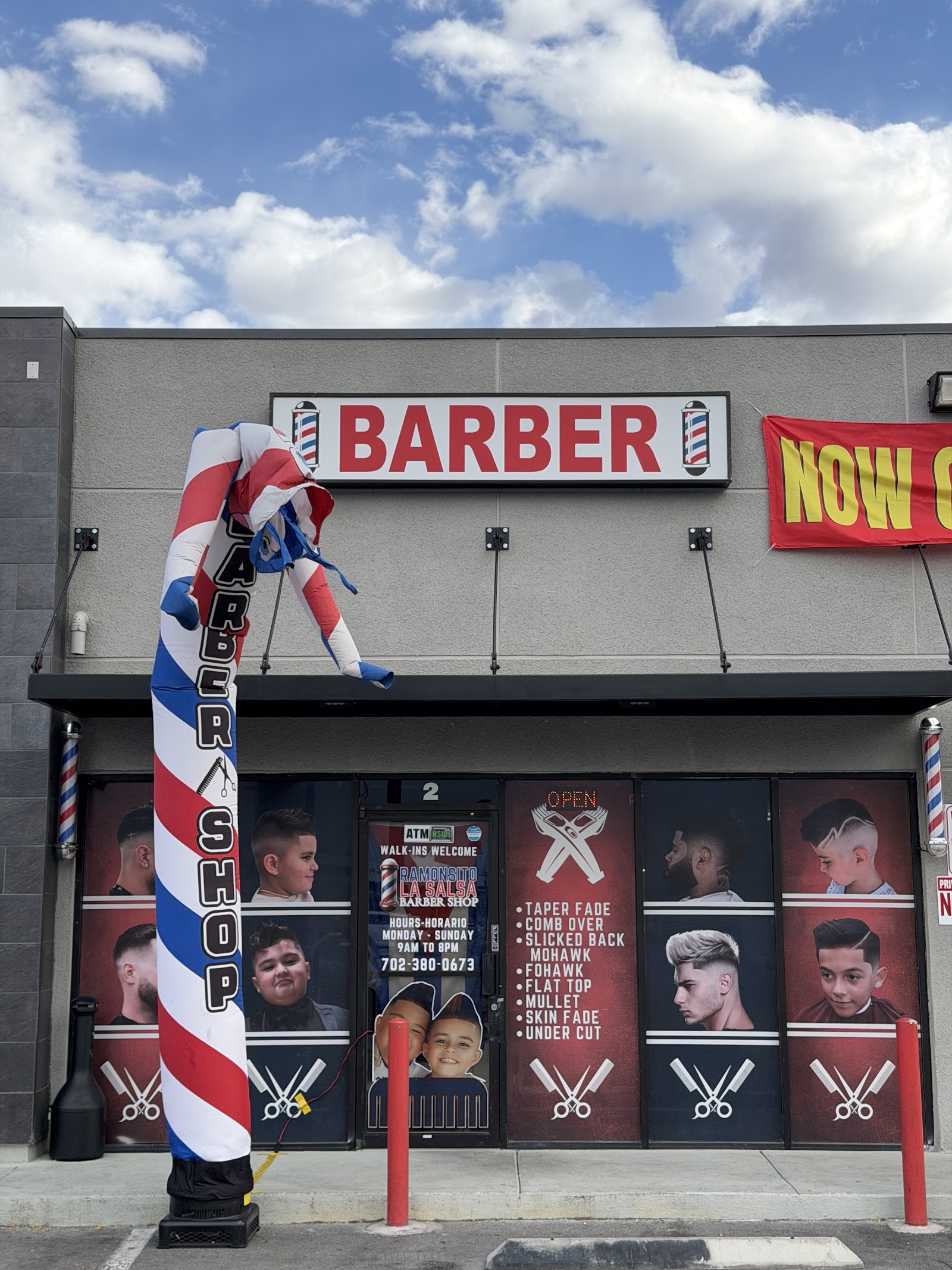 Exterior of Ramonsito La Salsa Barber Shop with BARBER sign, inflatable barber pole, and window graphics of haircut styles