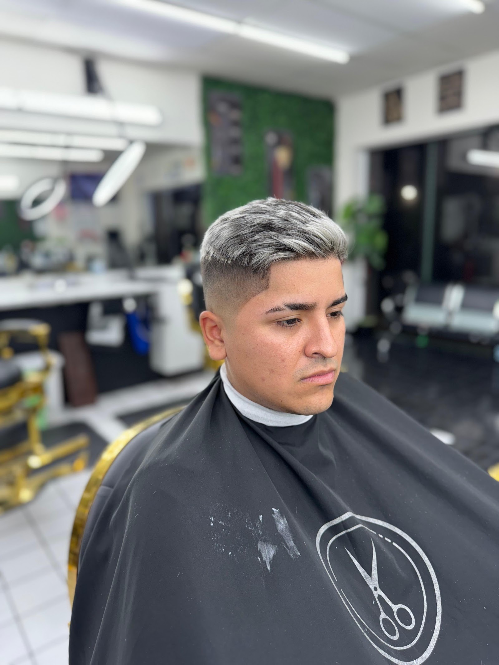 Man with silver-dyed textured quiff and skin fade wearing a barber cape