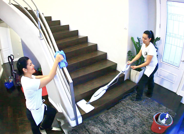 Two employees cleaning a staircase and railing in a home entryway