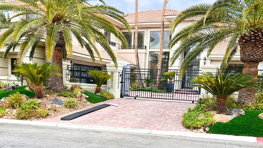 Upscale home entrance with palm trees, paver driveway and desert landscaping