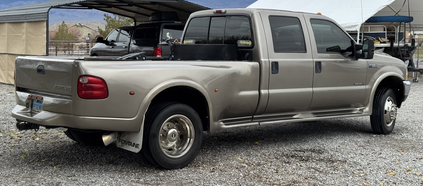Tan Ford F-550 crew cab dually diesel truck parked on gravel lot