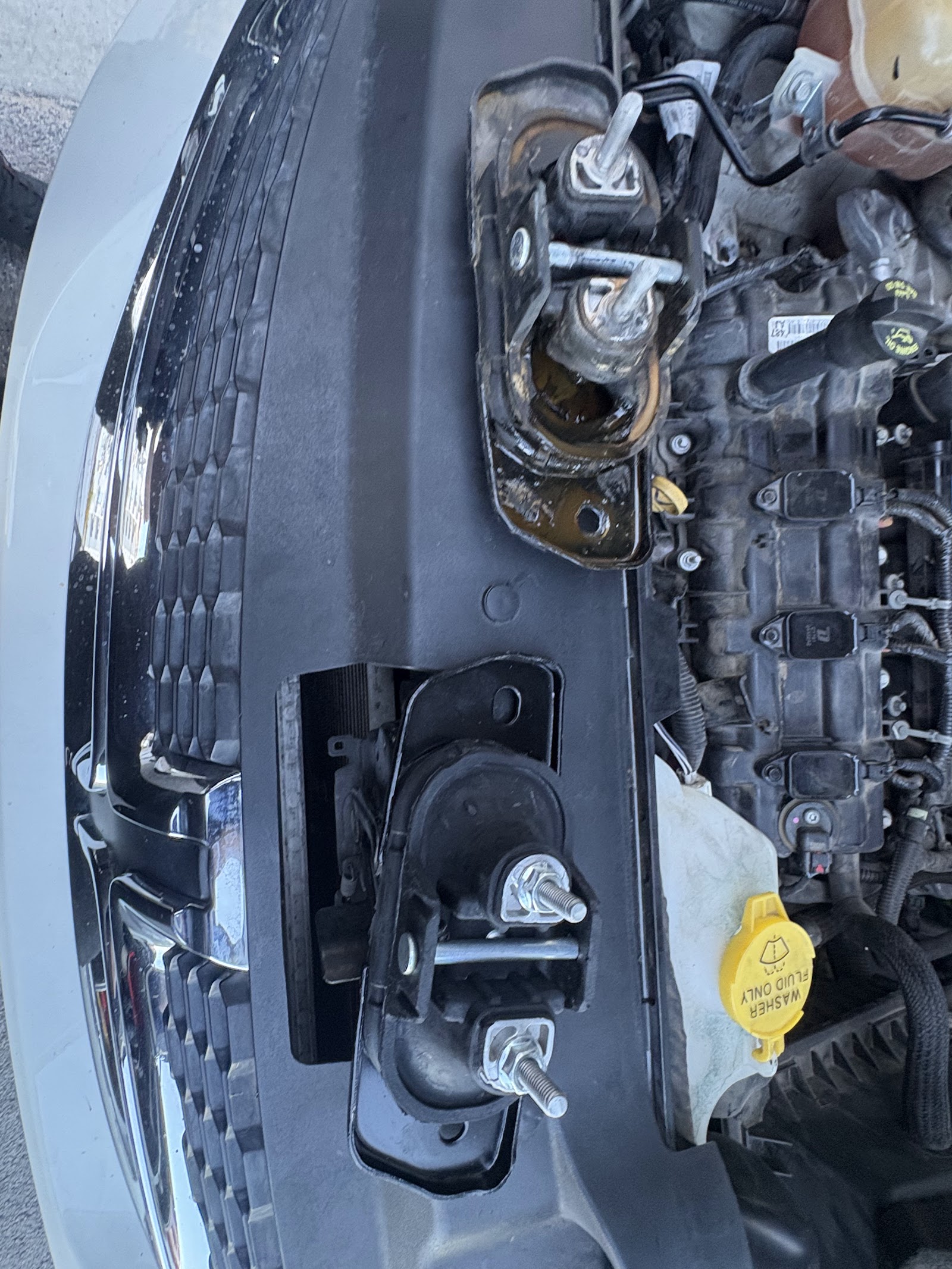 Front bumper and grille removed exposing engine mount and washer fluid reservoir