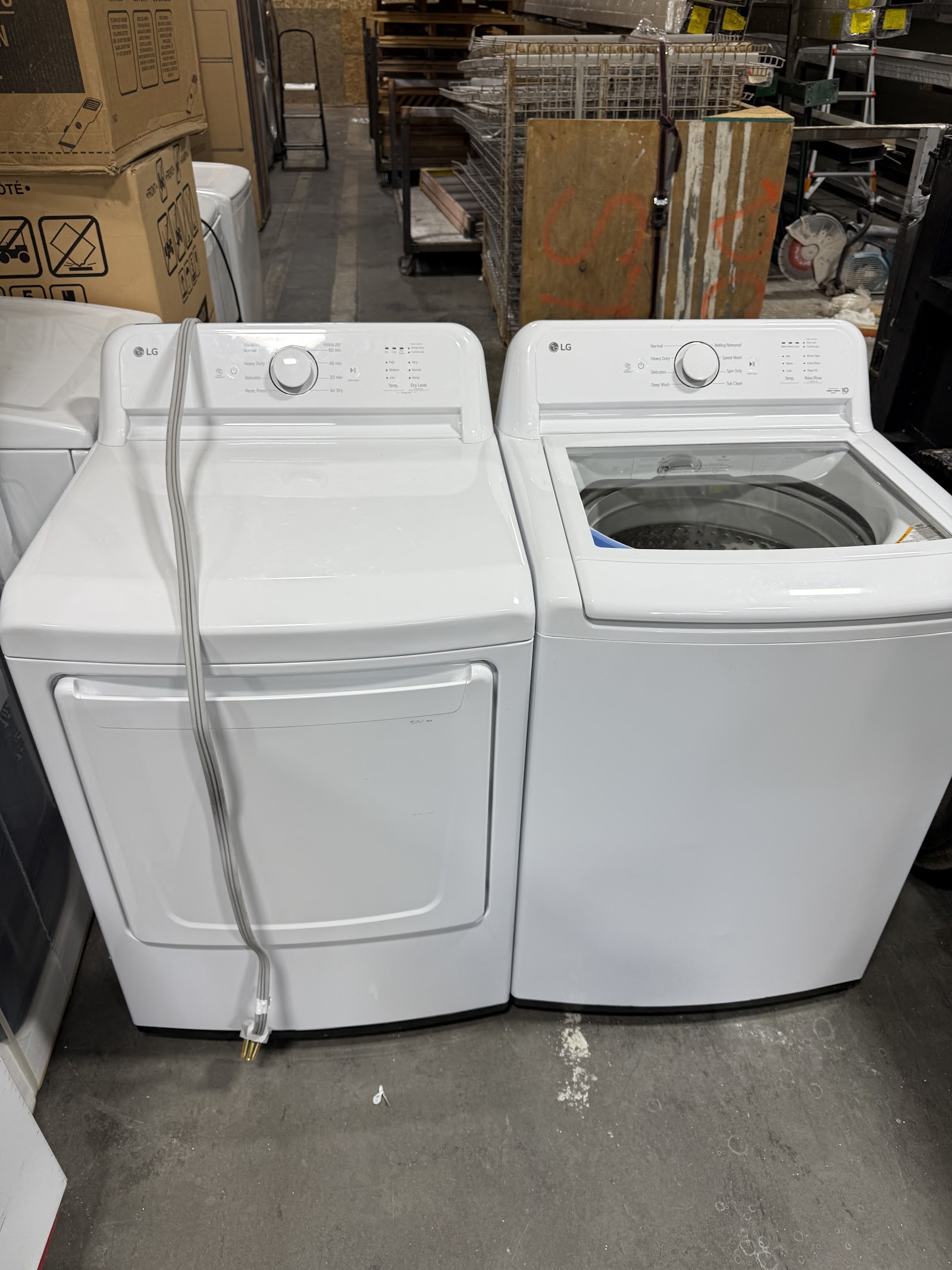 Pair of white LG top-load washer and dryer in warehouse