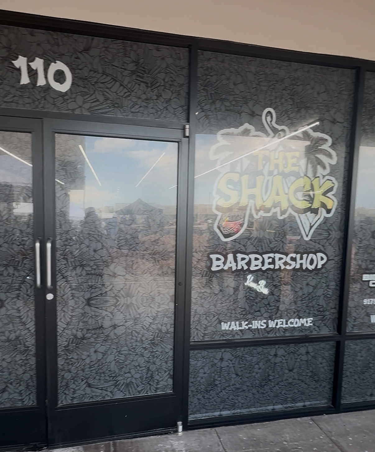 Storefront window with The Shack Barbershop logo and unit number 110