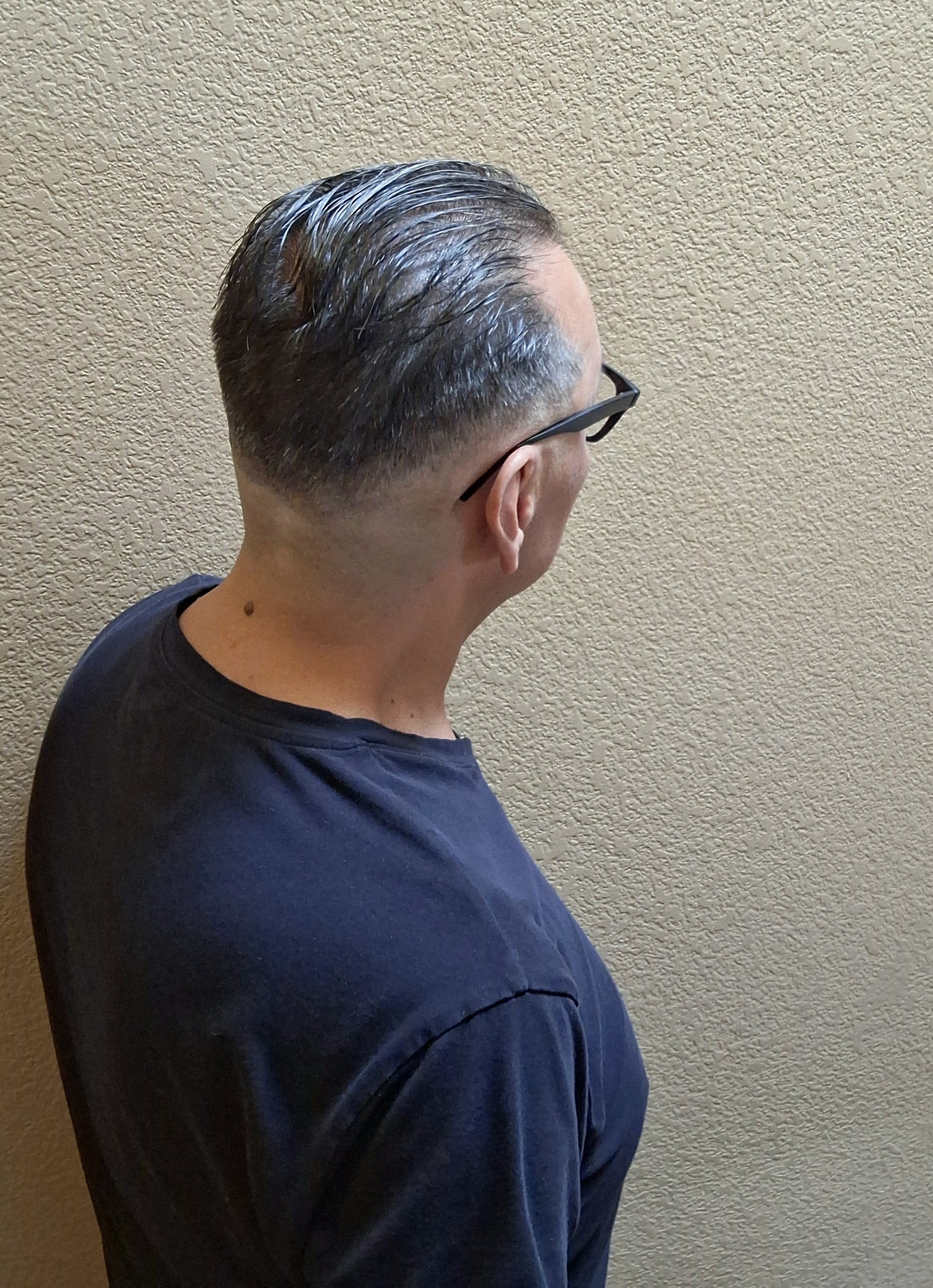 Back view of a men's tapered haircut with slicked-back styling