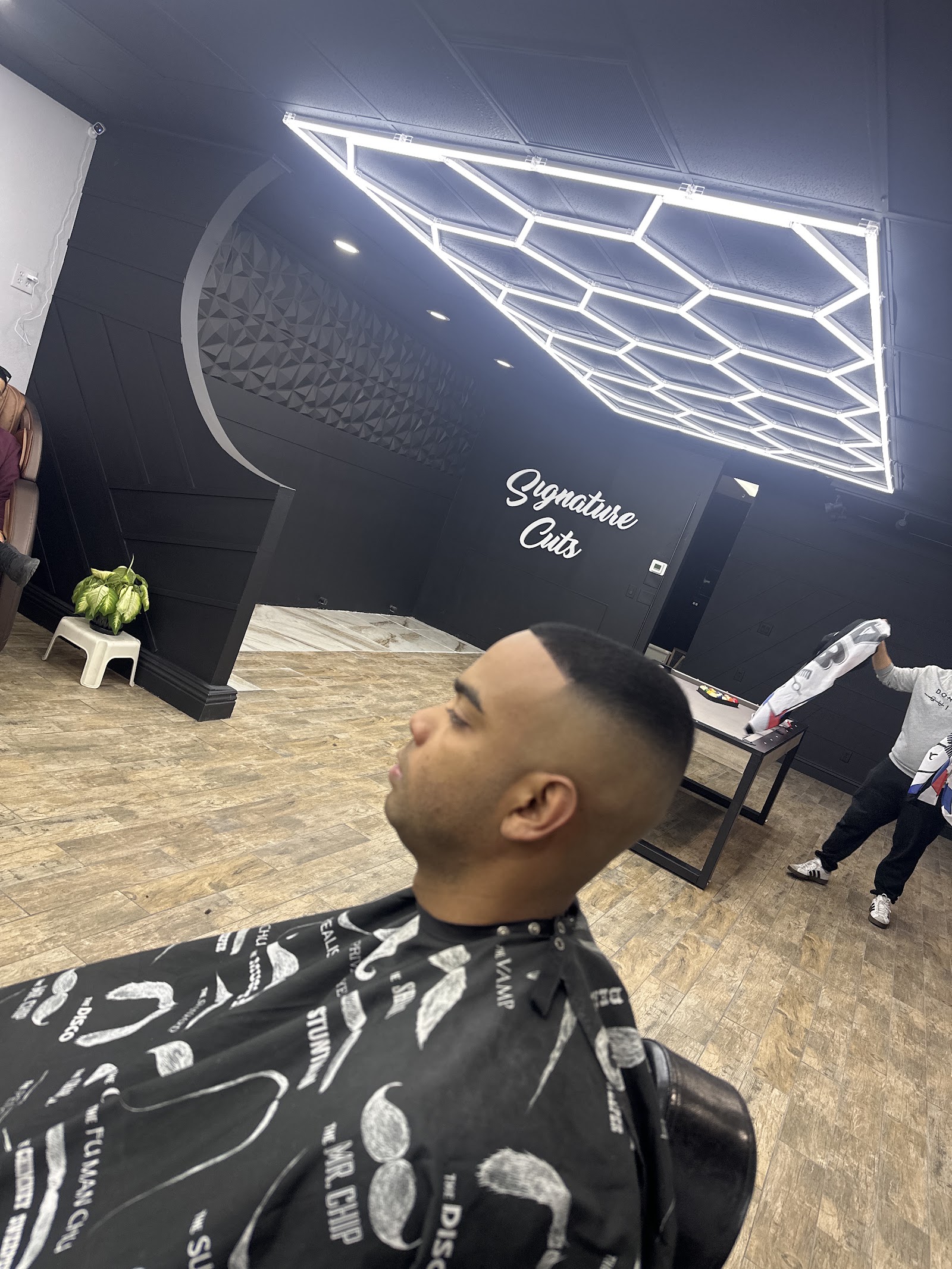 Client with a clean skin fade seated in barber chair, Signature Cuts interior visible