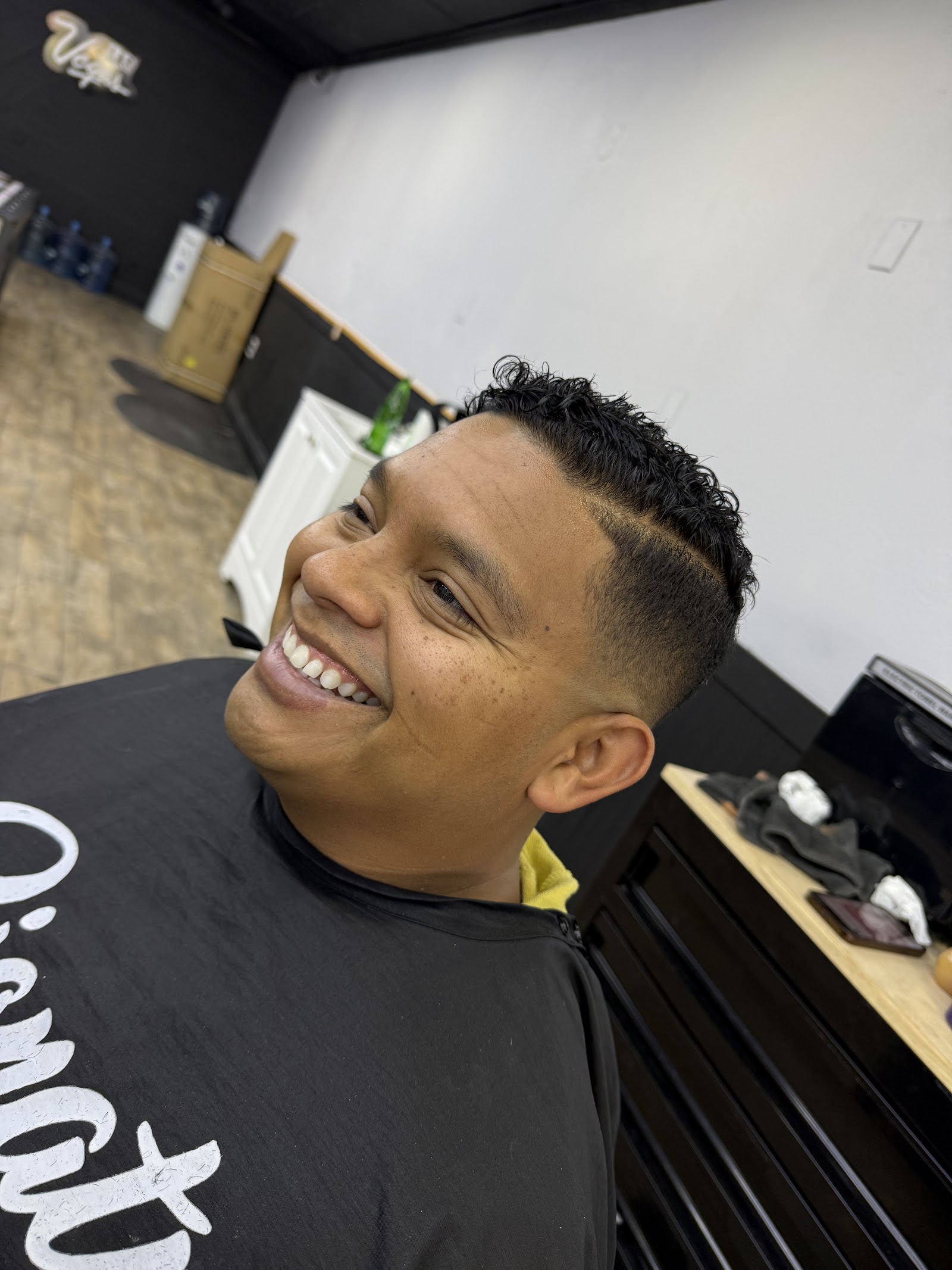 Smiling client with curly top and skin fade haircut in barbershop