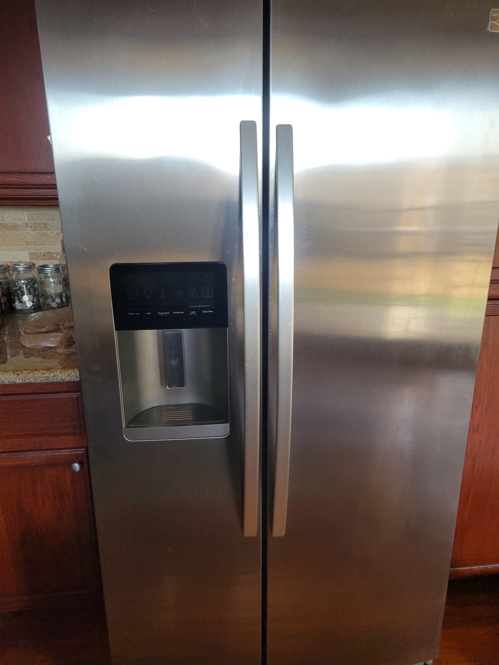 Stainless steel side-by-side refrigerator with water and ice dispenser in a home kitchen