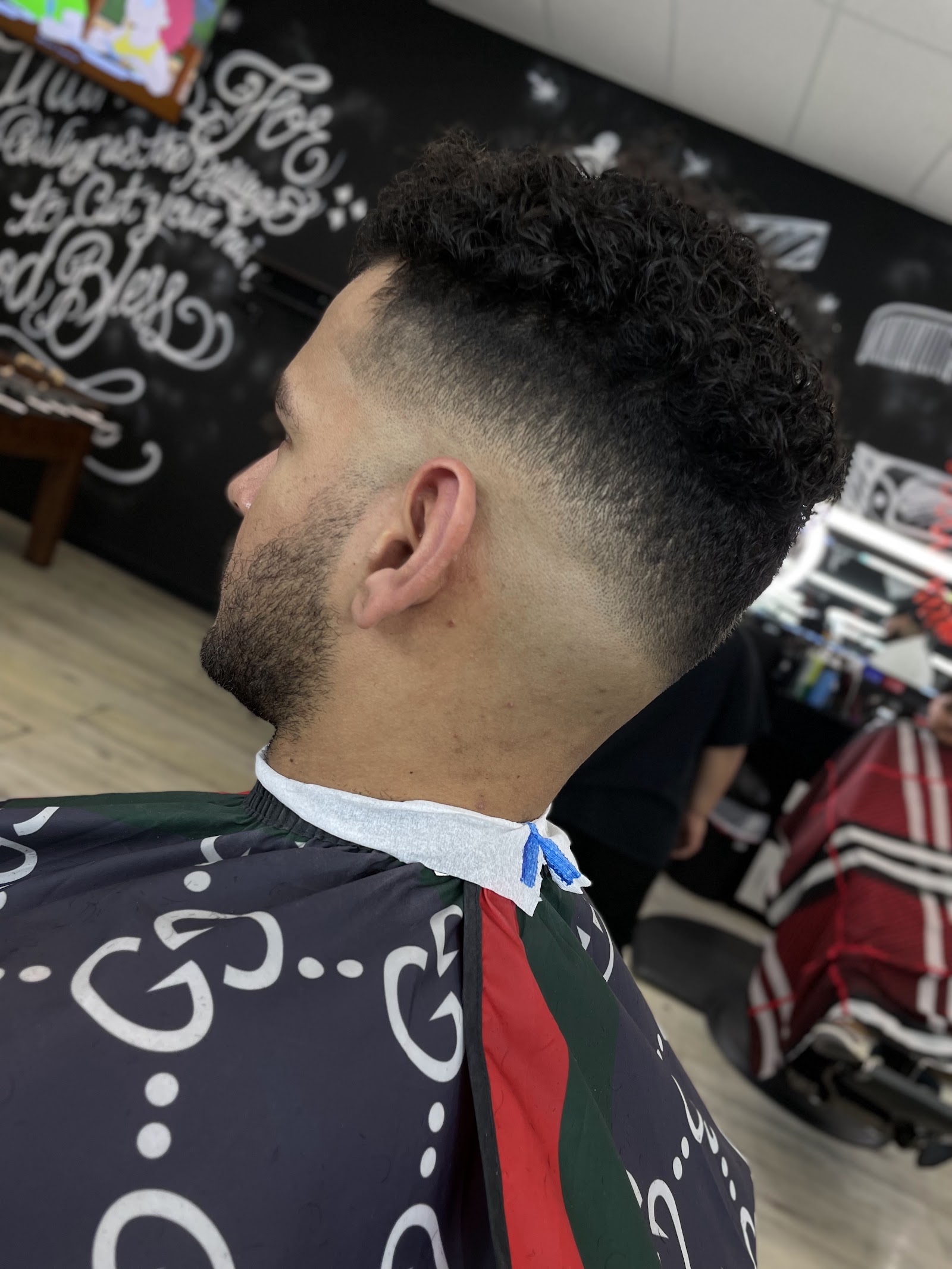Side profile of client with curly top and skin fade