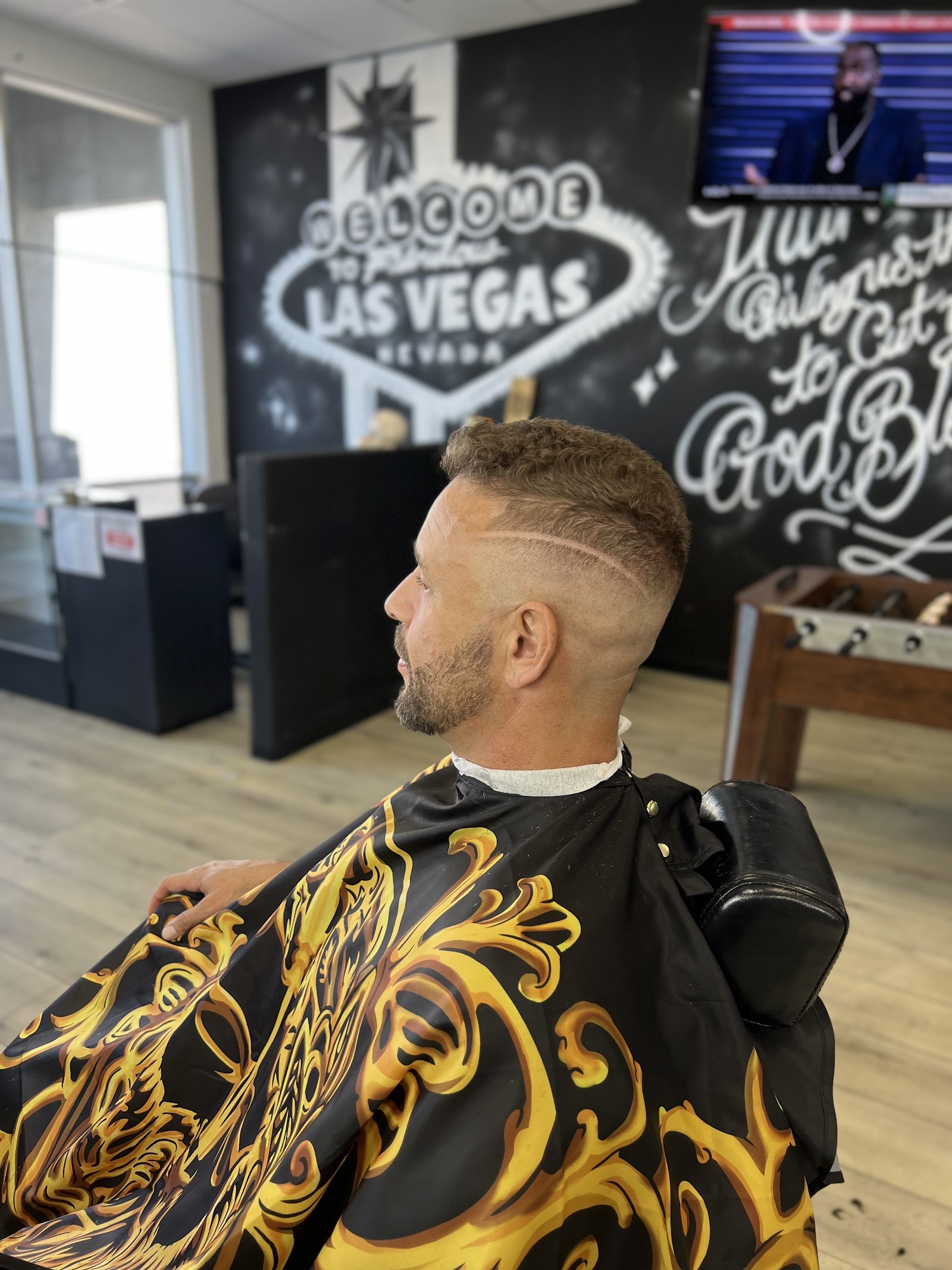 Client with curly top fade and shaved line design in barbershop interior