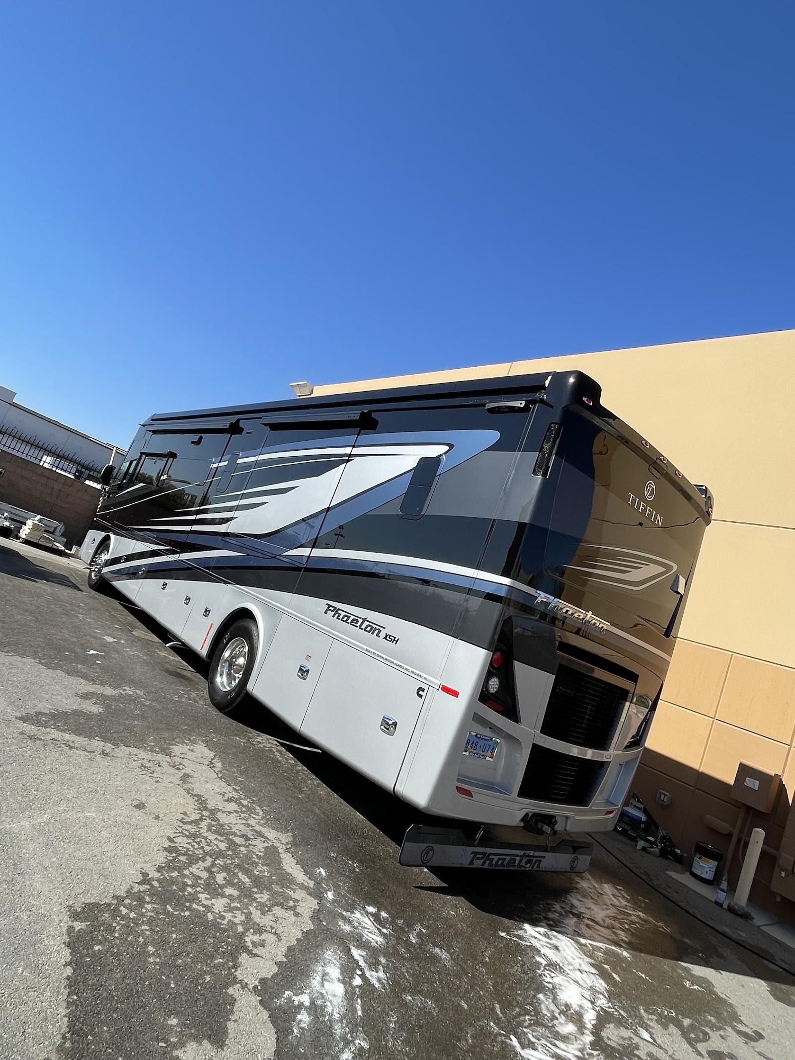 Detailed Tiffin Phaeton motorhome RV parked beside commercial building
