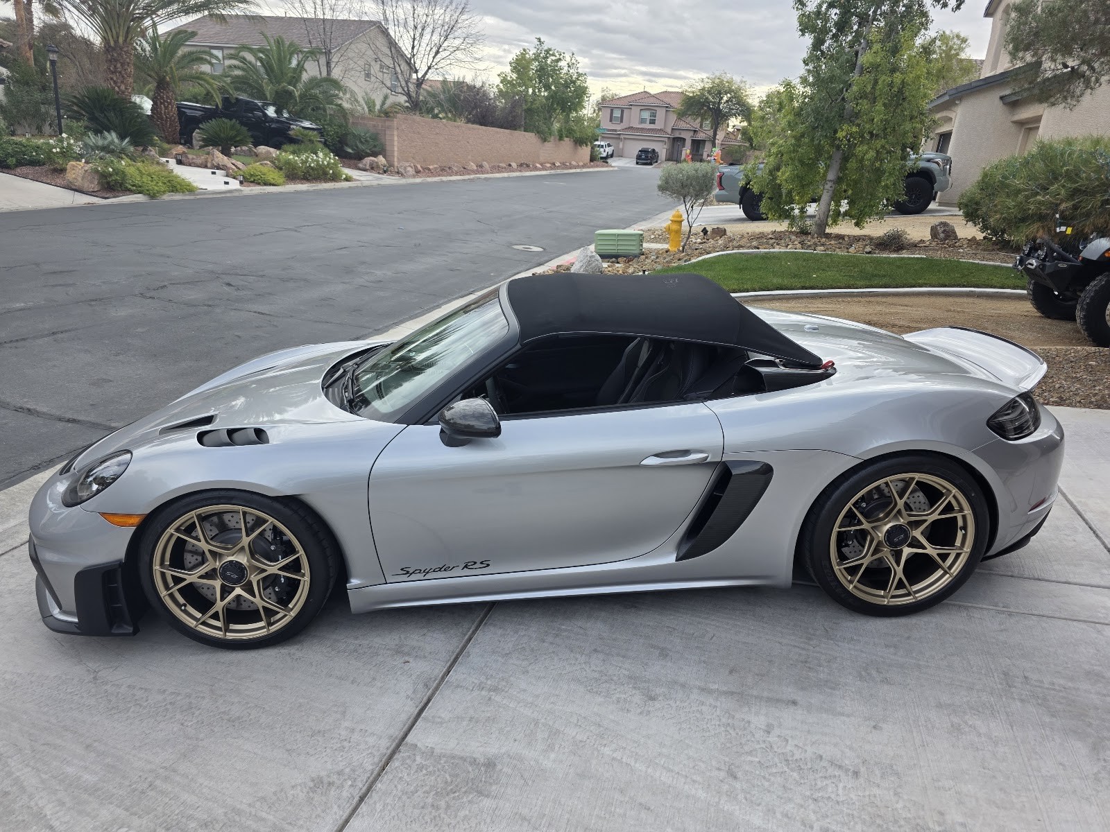 Detailed silver Porsche 718 Spyder RS with bronze wheels in driveway
