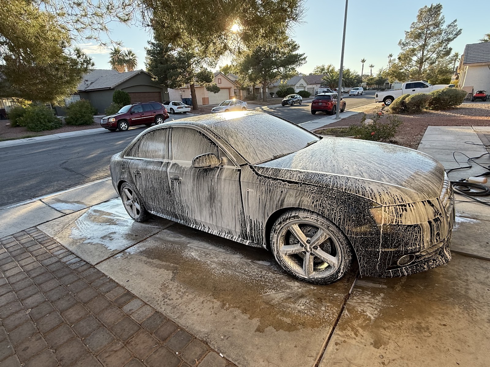 Audi sedan covered in foam soap during wash on driveway