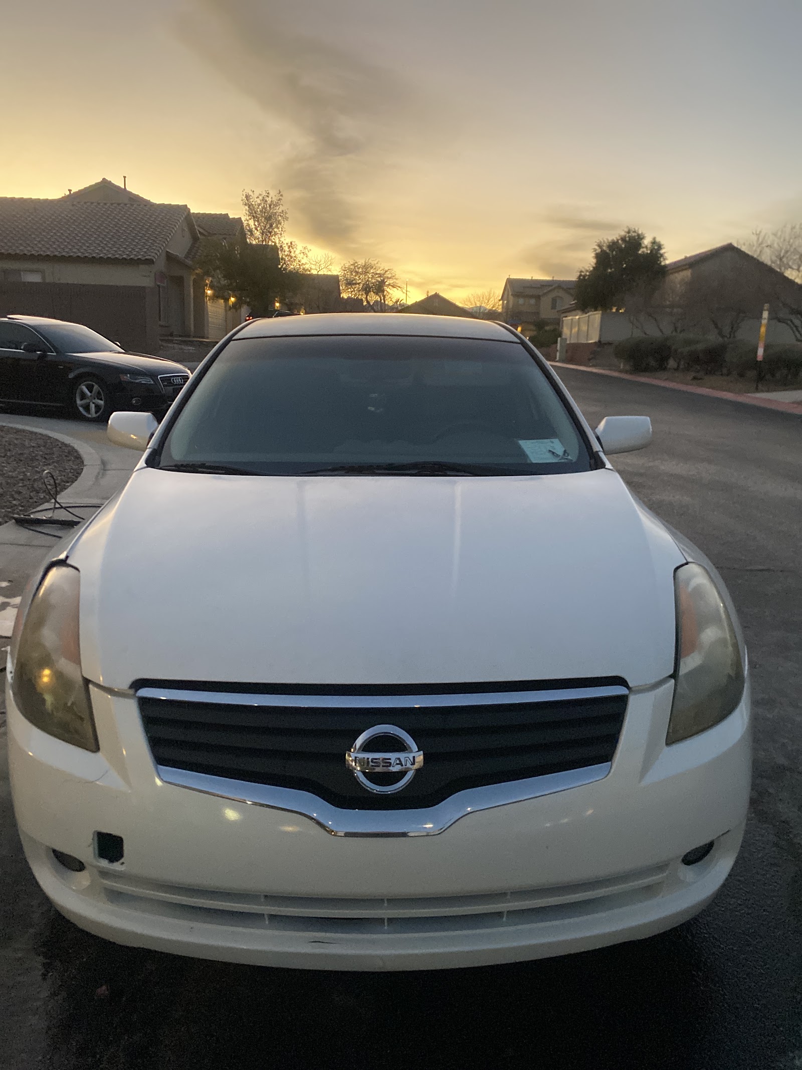 White Nissan Altima detailed at sunset in residential driveway