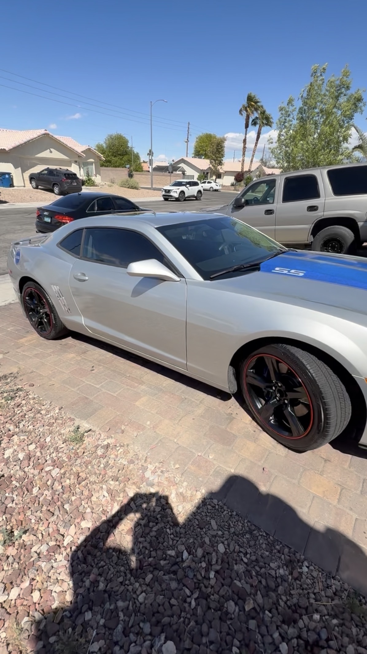 Silver Chevrolet Camaro SS with blue racing stripe in driveway