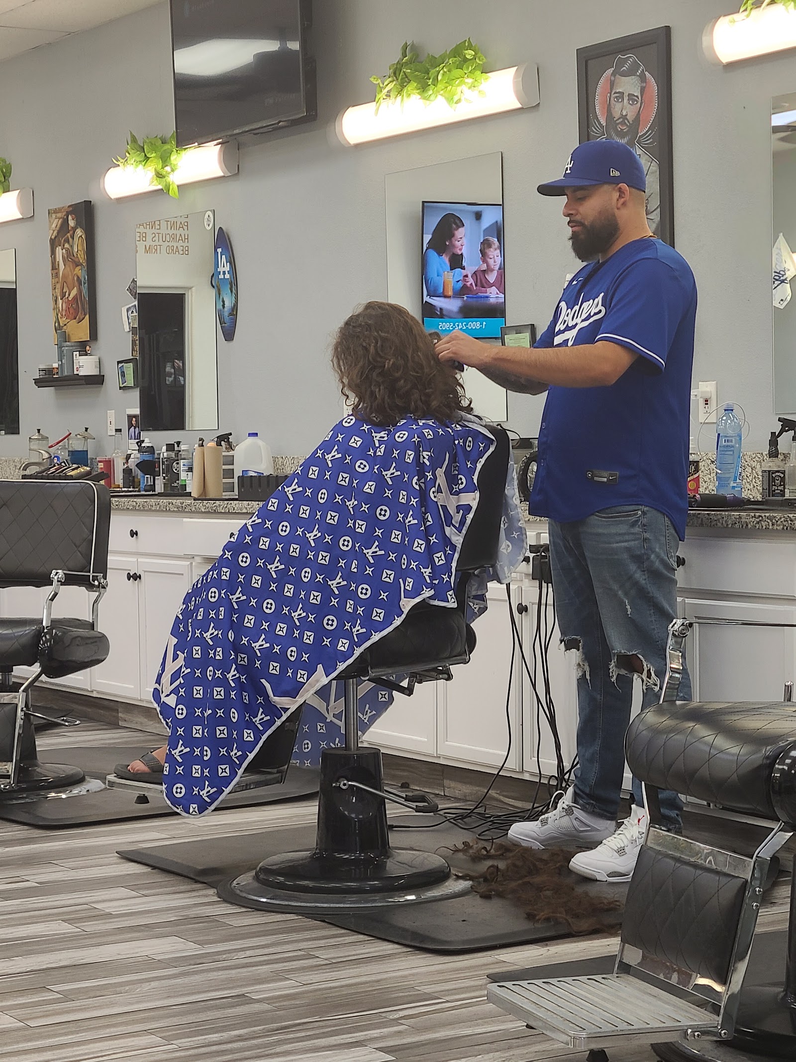 Barber in Dodgers jersey cutting a client's curly hair