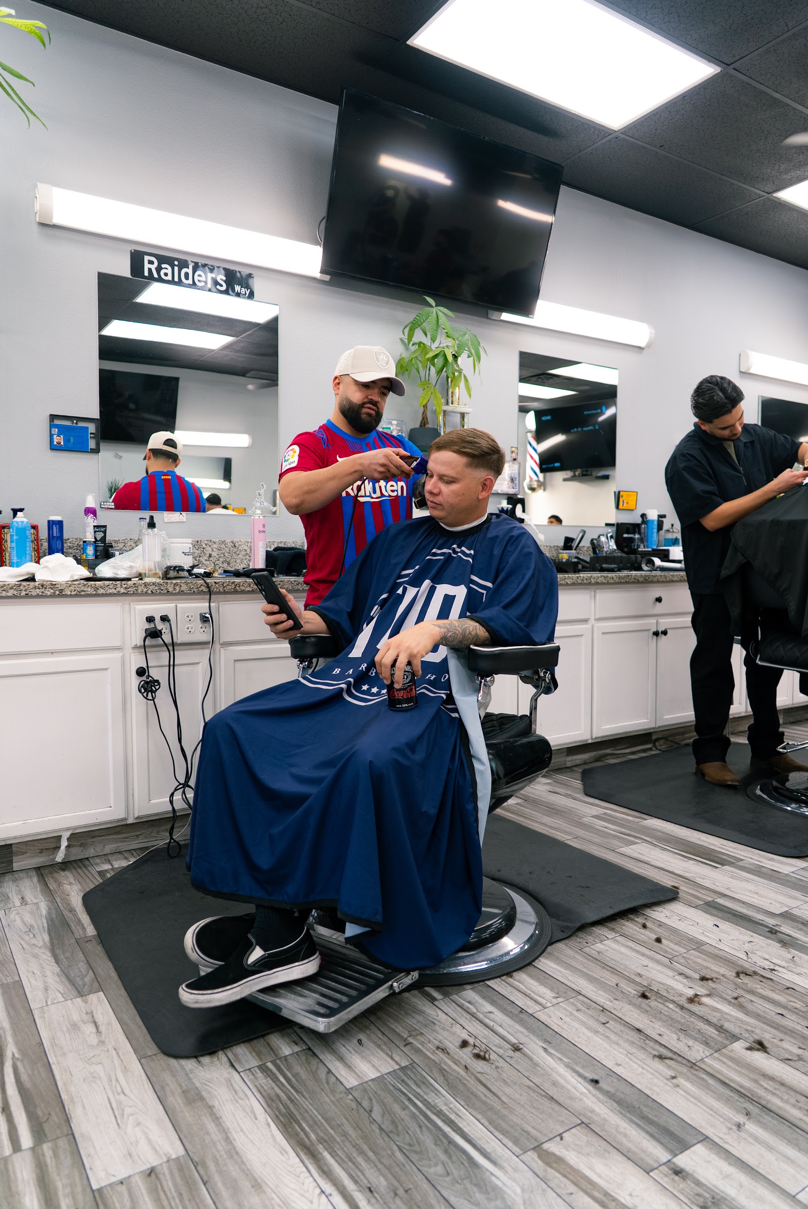 Barber trimming a seated client's hair with clippers in the barbershop