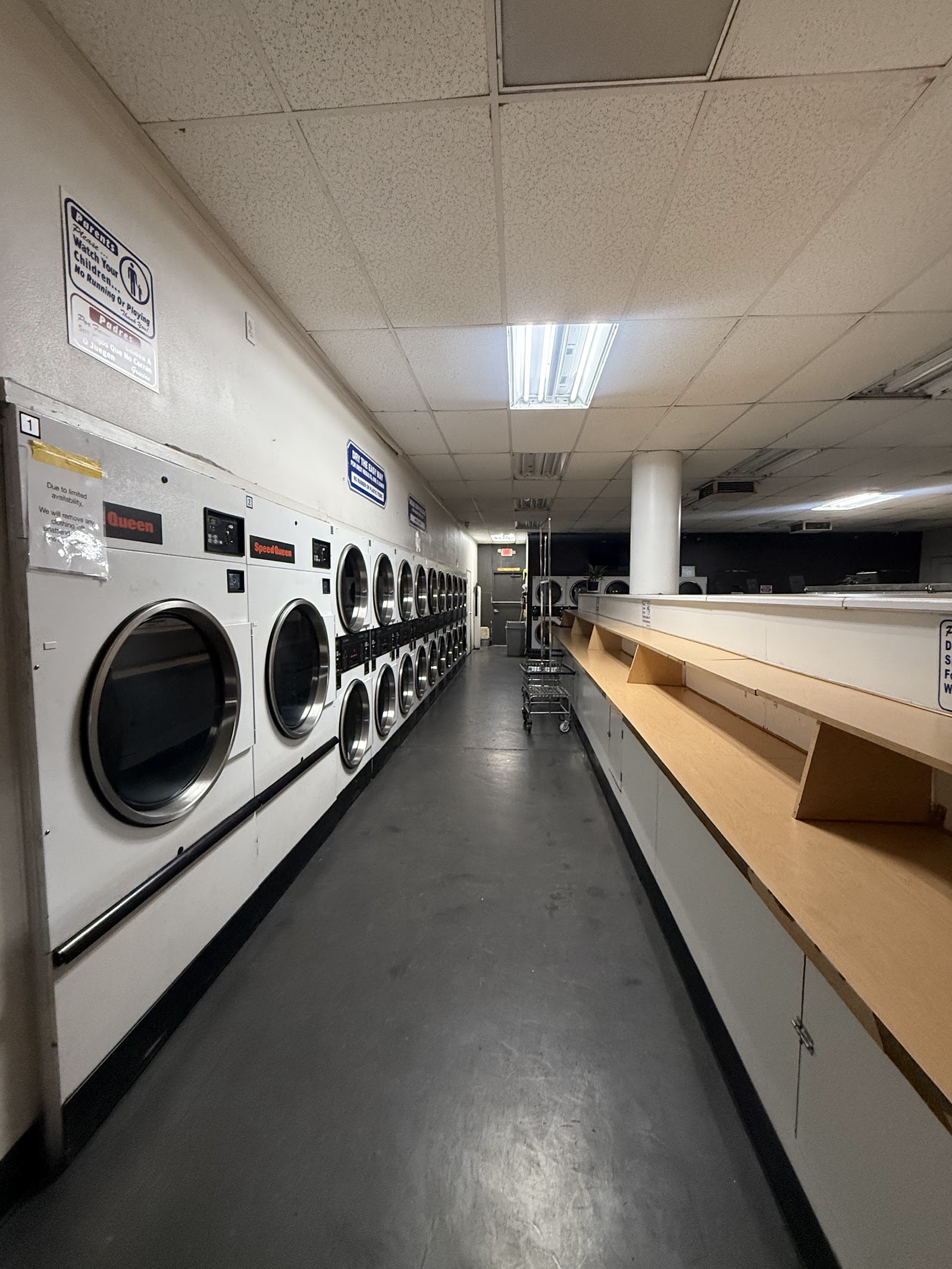 Long aisle of Speed Queen washers and dryers with folding shelves
