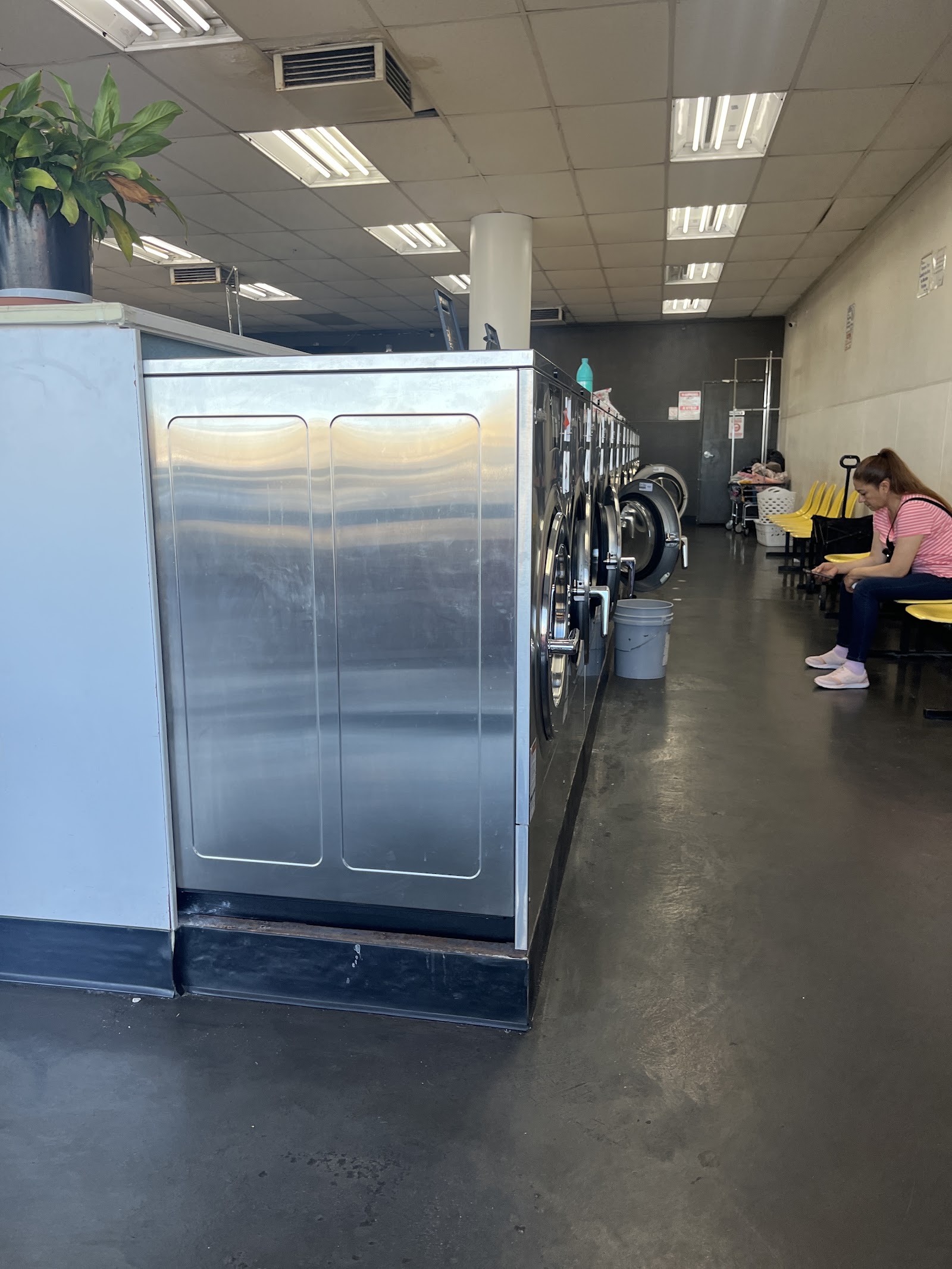 Large stainless washers lined up with seating area and a waiting customer