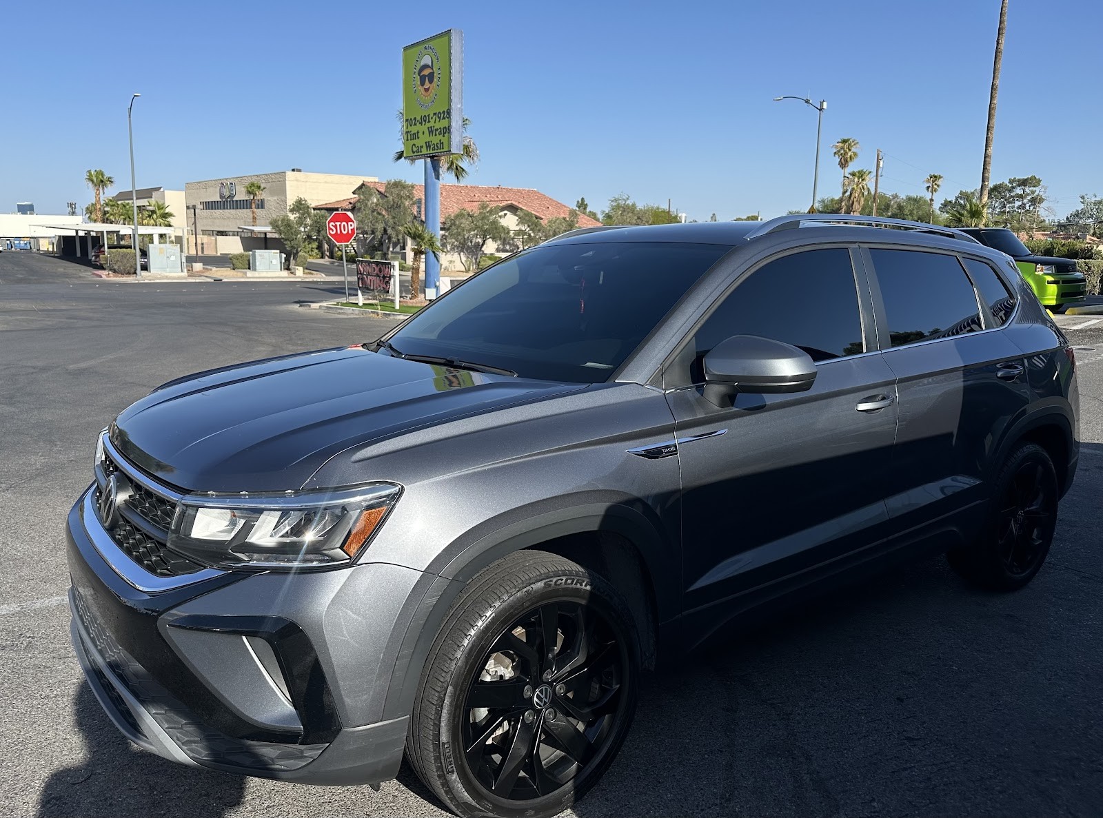 Gray VW Taos SUV with tinted windows and shop pole sign in background