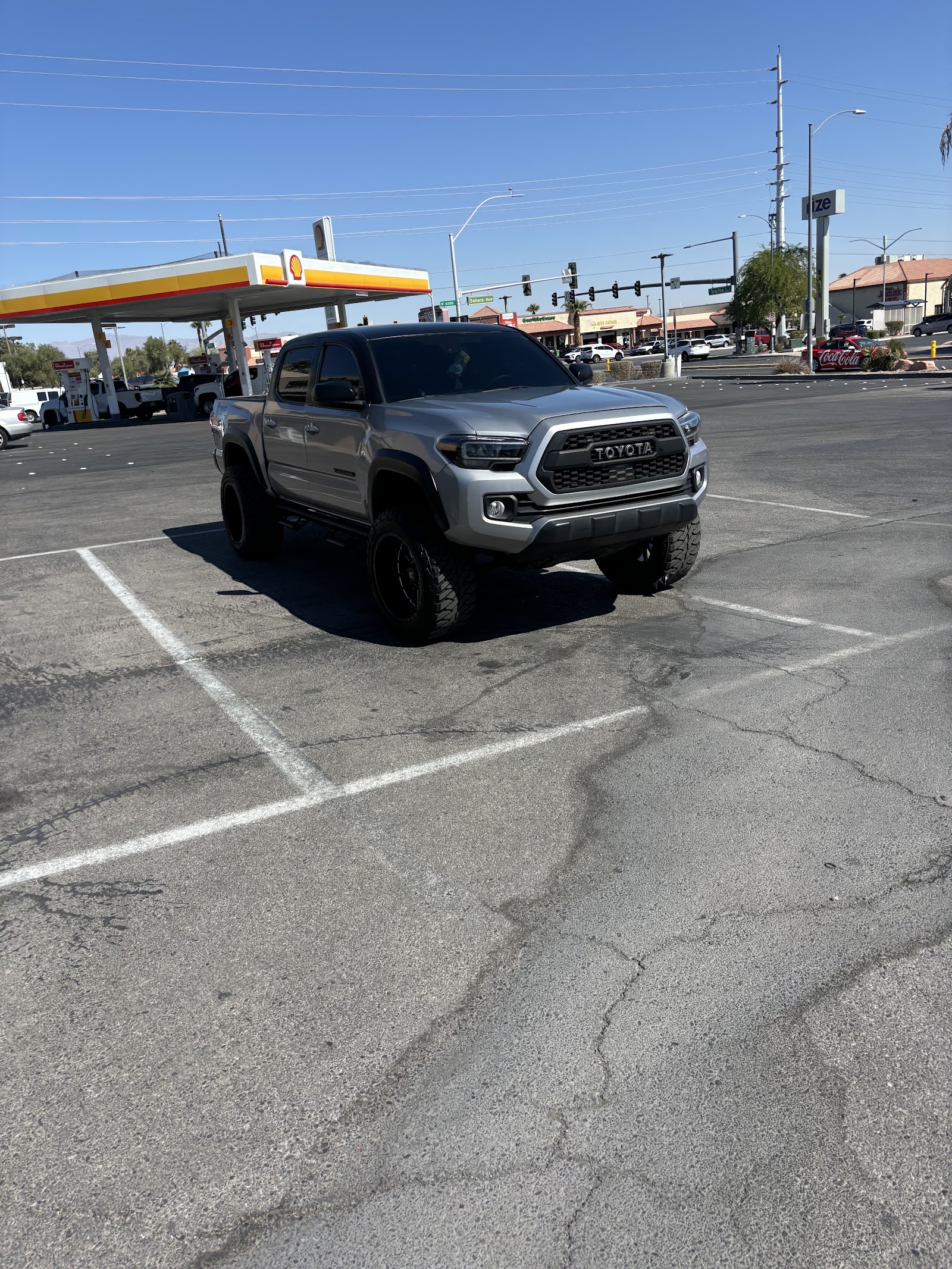 Lifted silver Toyota Tacoma TRD with dark tinted windows at gas station