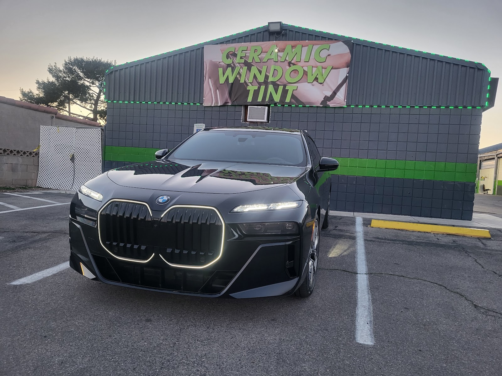 Black BMW 7 Series in front of Ceramic Window Tint banner at the shop
