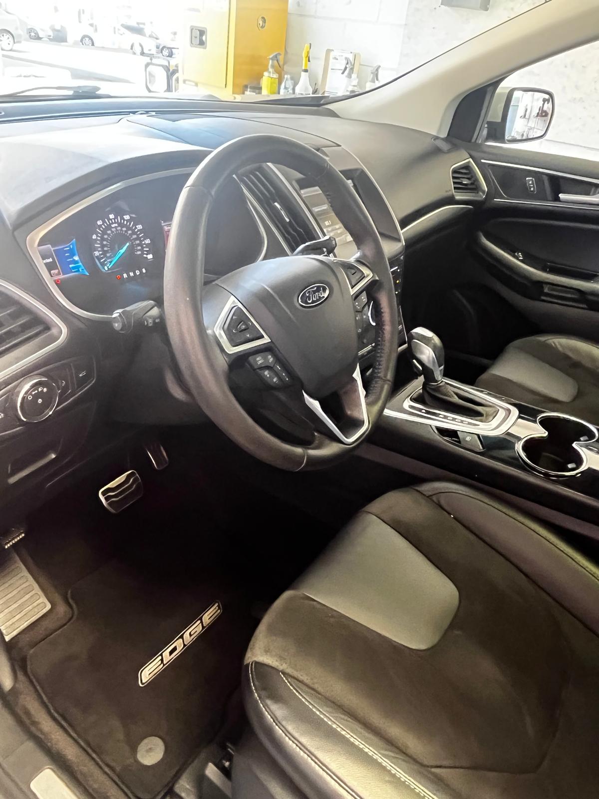 Clean interior of a Ford Edge showing steering wheel, dash, and console