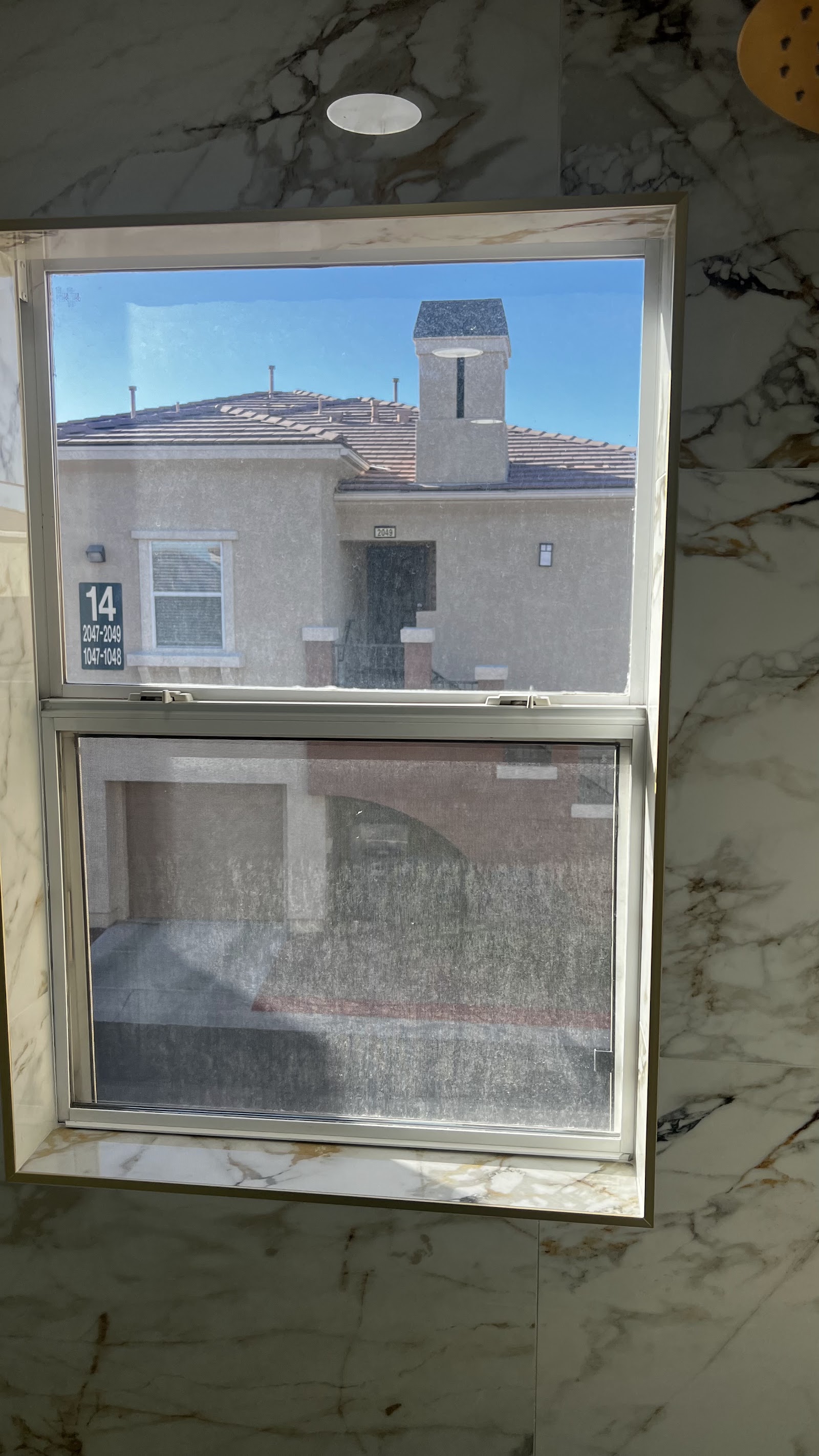 Tinted residential double-hung window in marble-tiled room