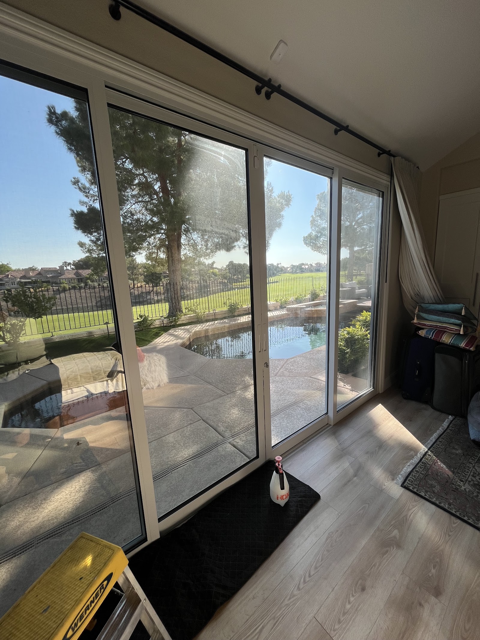 Interior sliding glass door being cleaned with tinting tools and ladder