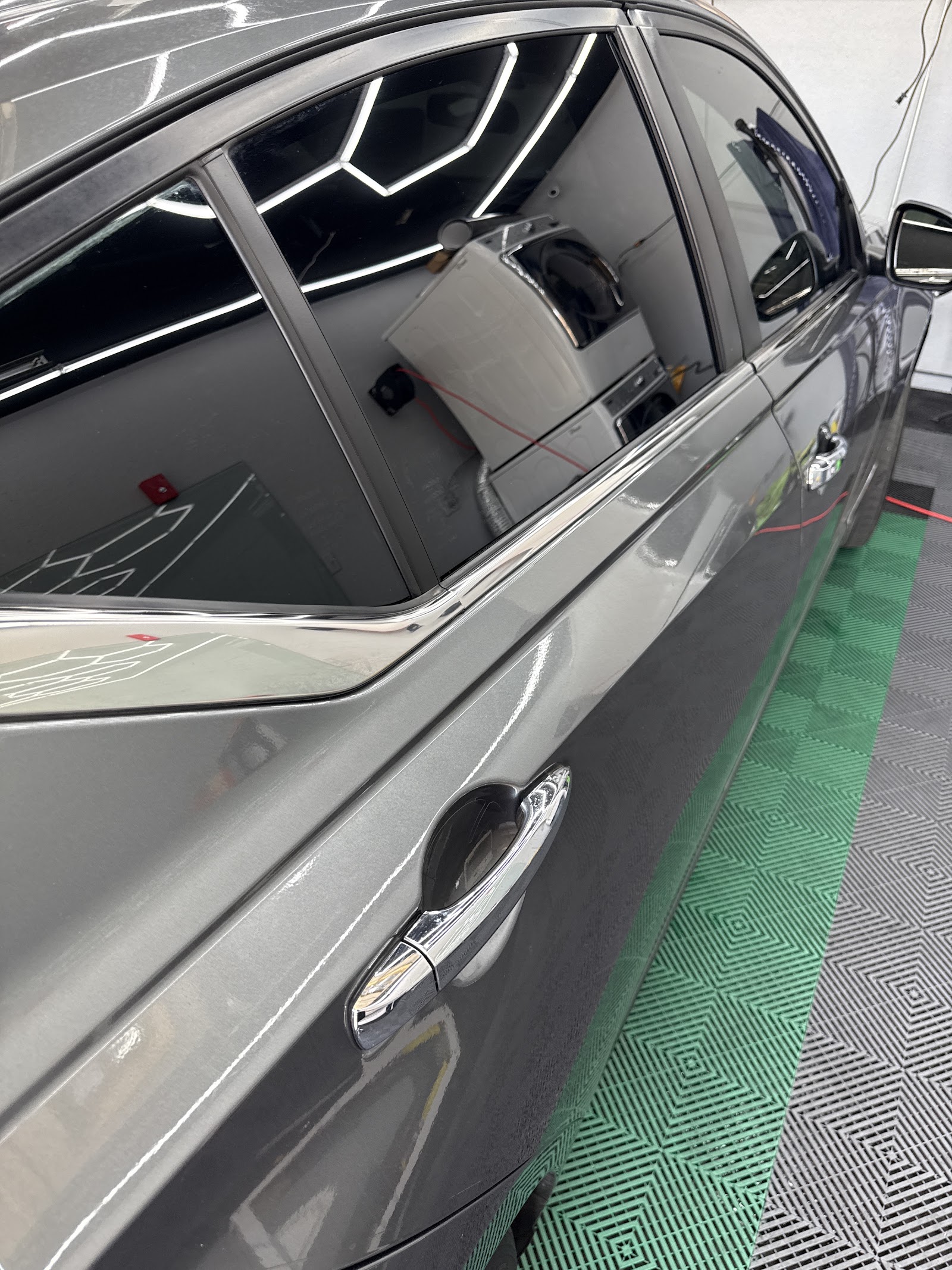Close-up of gray sedan with freshly tinted windows on shop floor