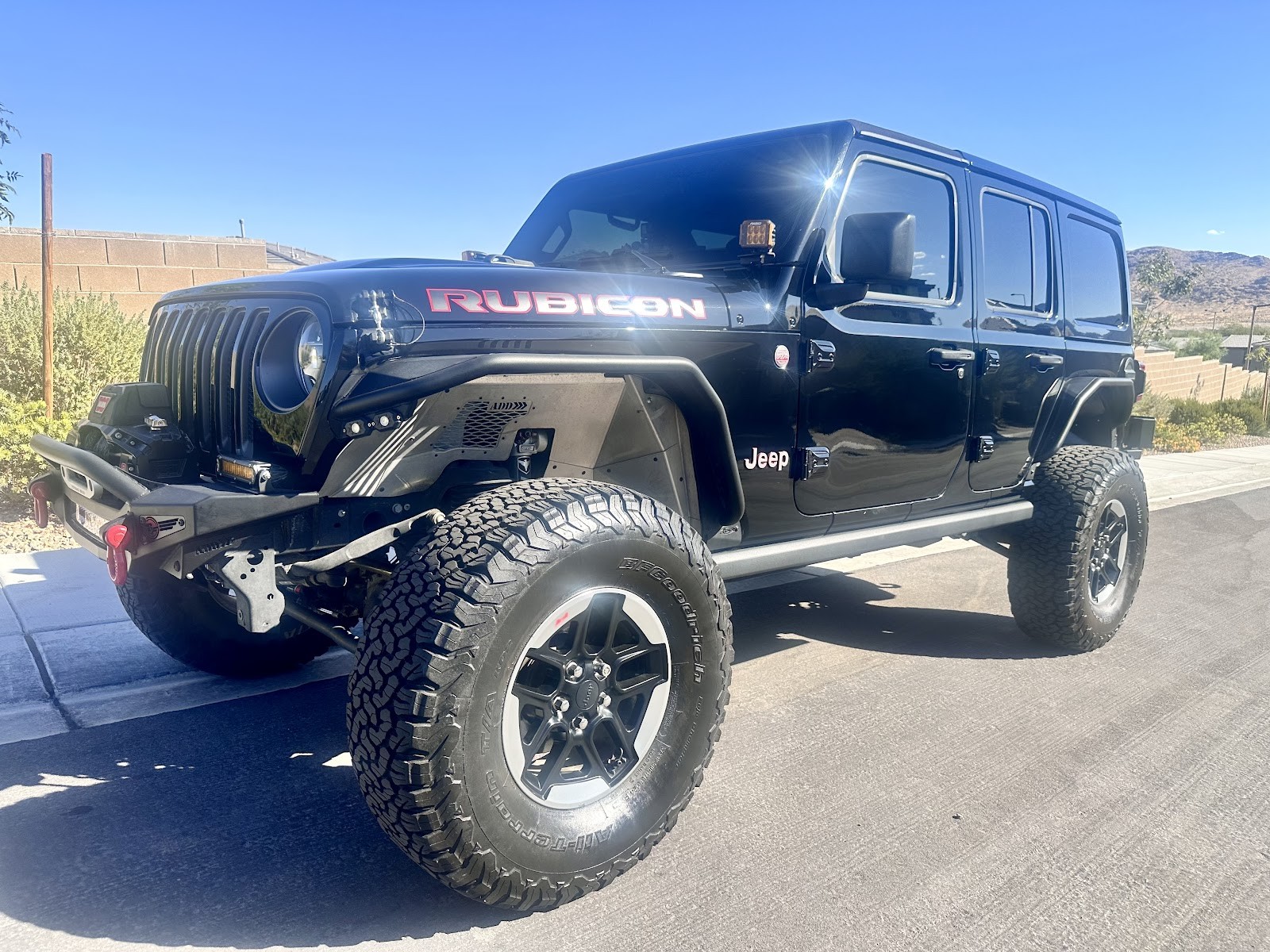 Black lifted Jeep Wrangler Rubicon detailed and shiny against desert backdrop