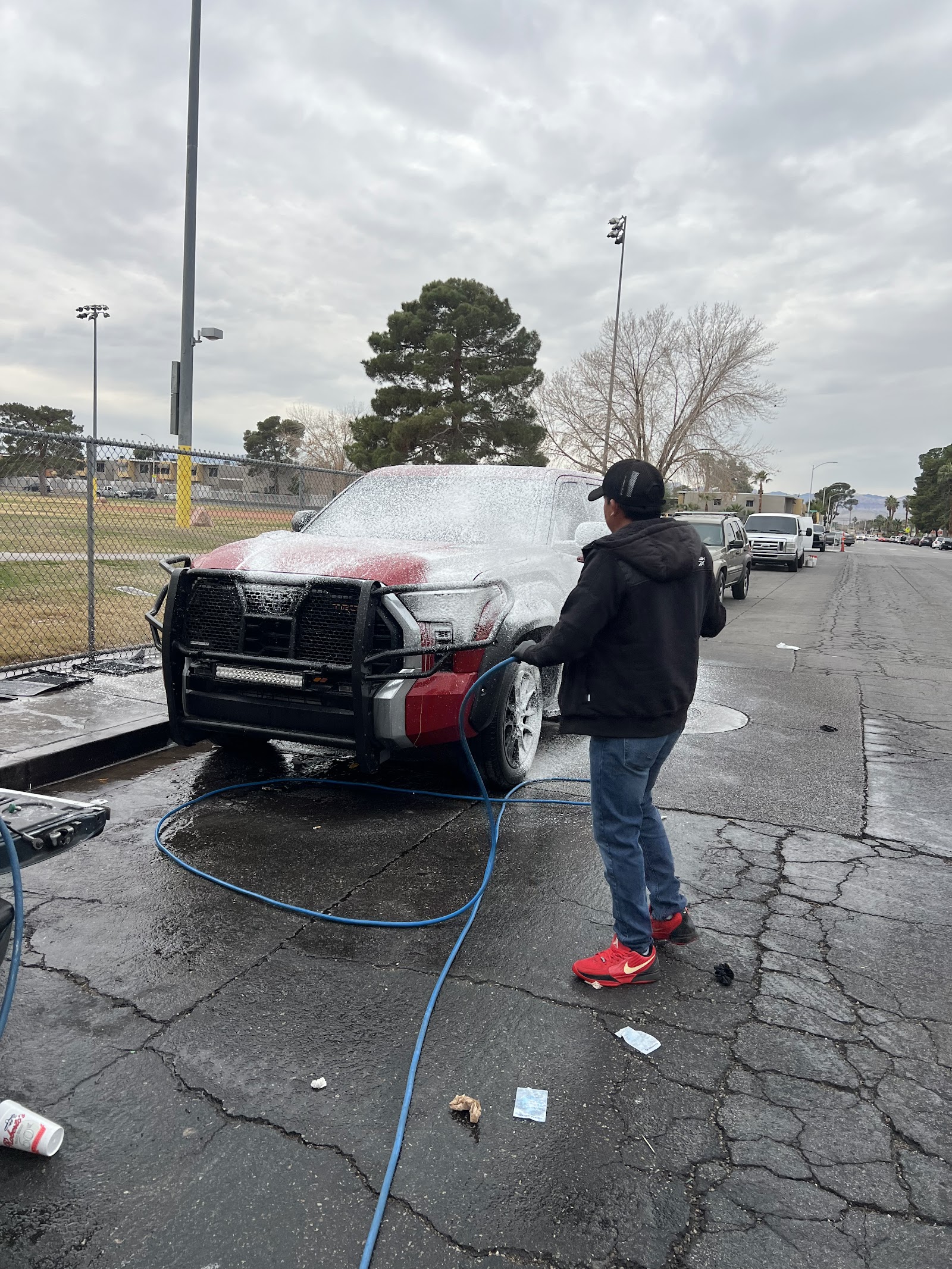 Worker foam-washing a red Toyota Tundra truck