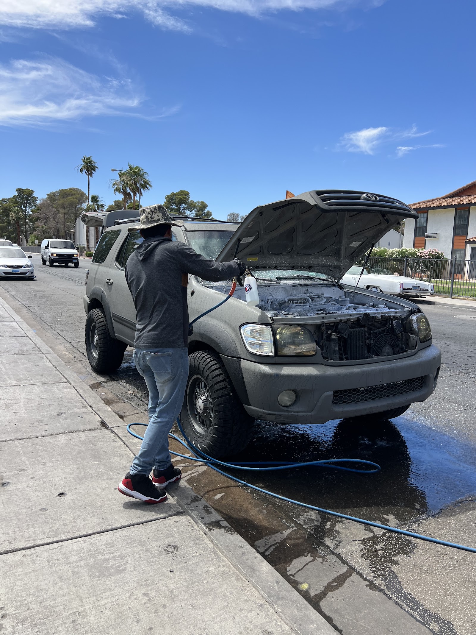 Detailer cleaning engine bay of a Toyota Sequoia with hood open