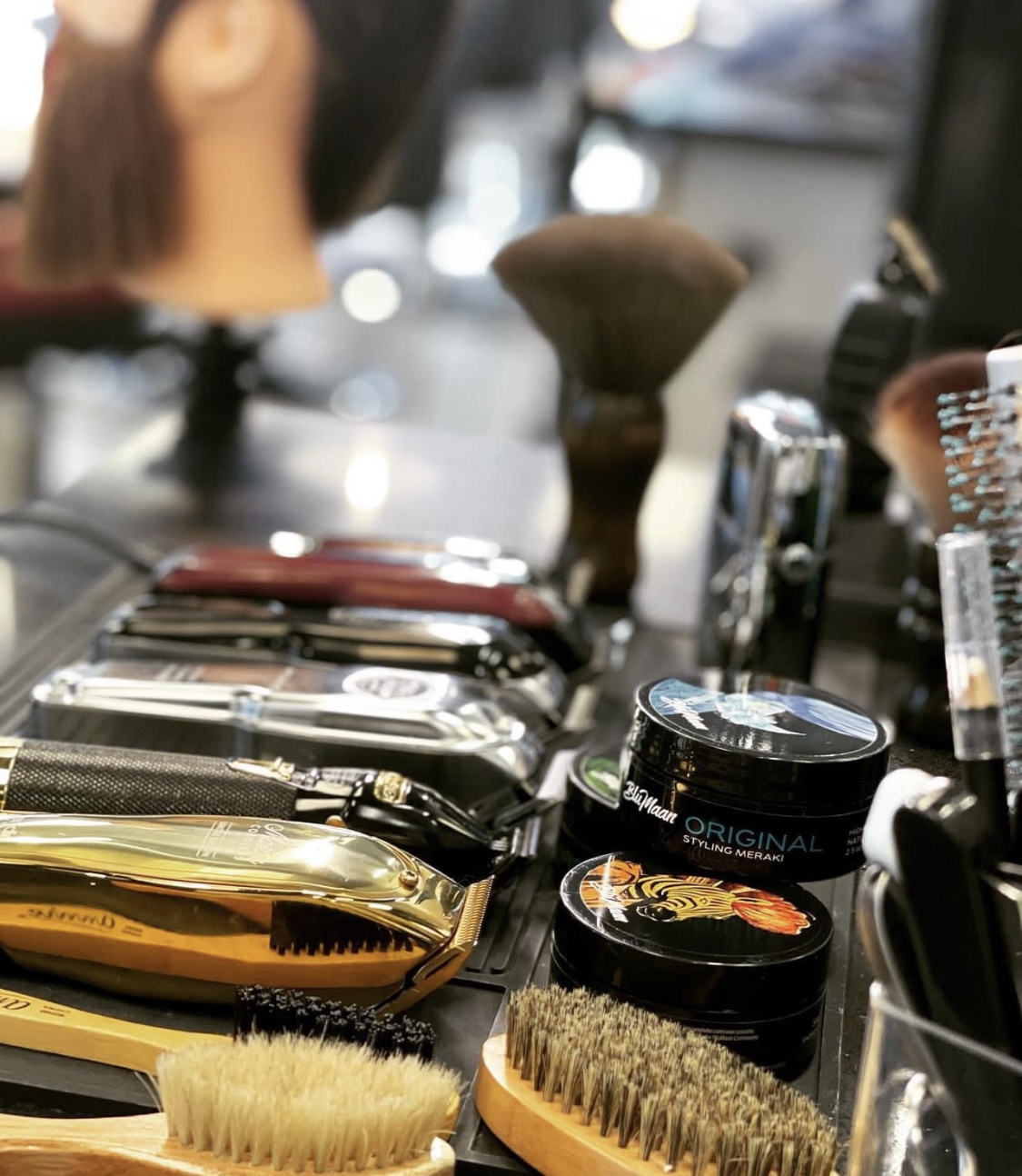 Barber tools including clippers, brushes and styling products on counter