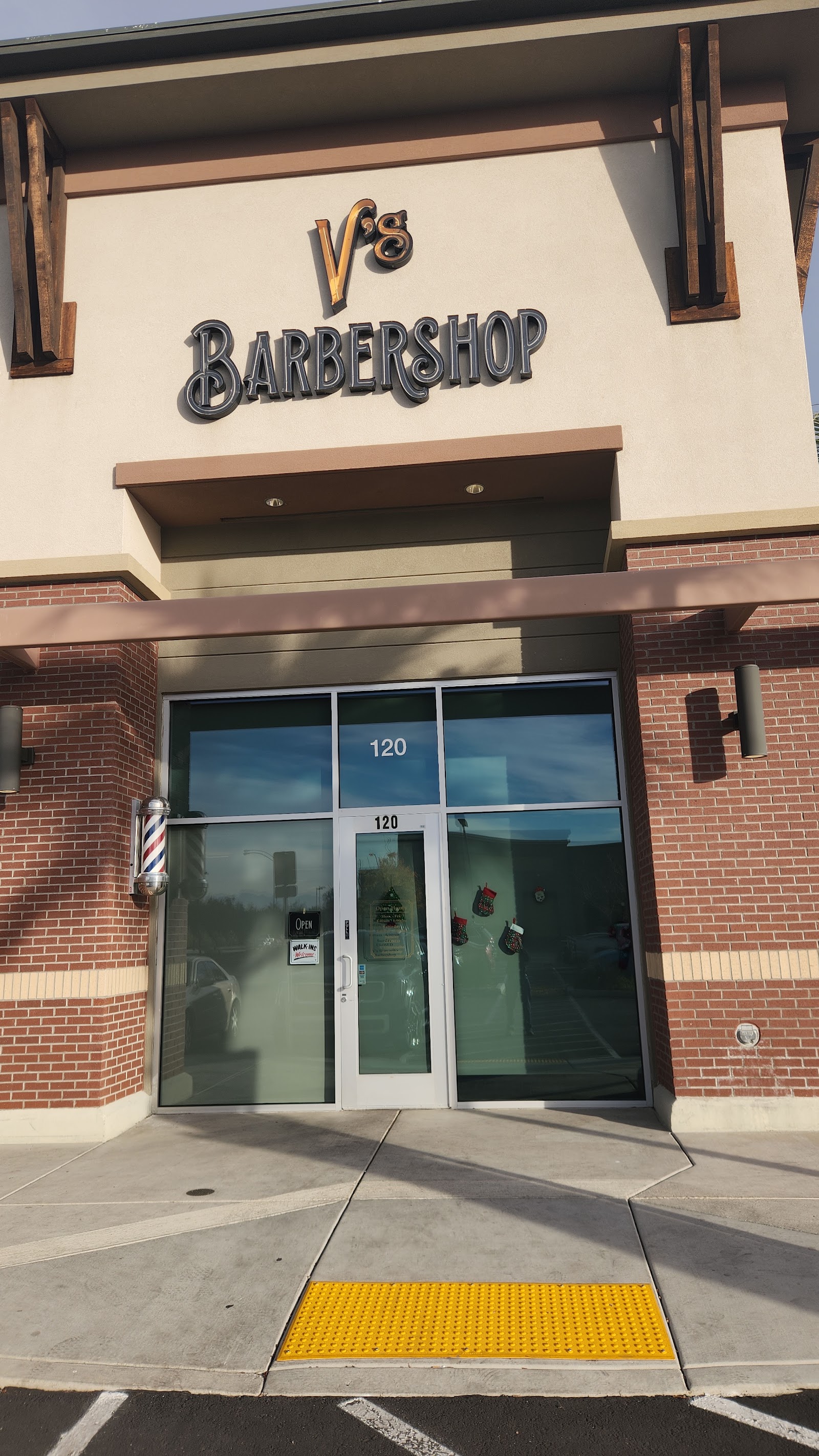 Exterior of V's Barbershop with signage, barber pole and suite 120 entrance