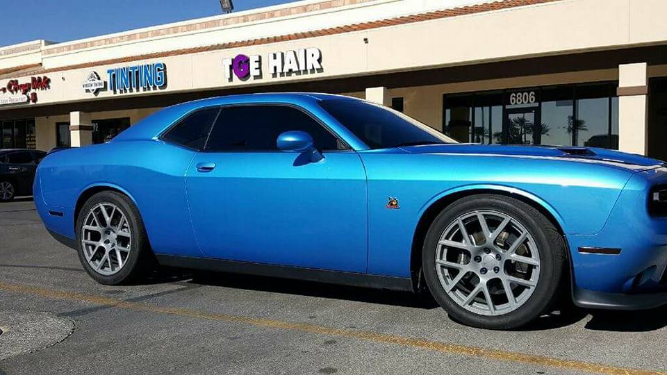 Blue Dodge Challenger with tinted windows in front of the shop