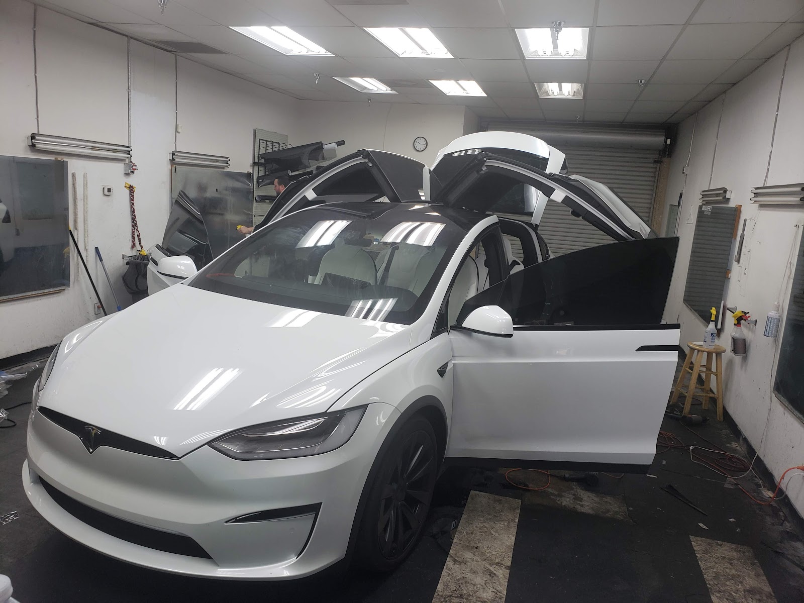 White Tesla Model X with doors open being tinted in a shop
